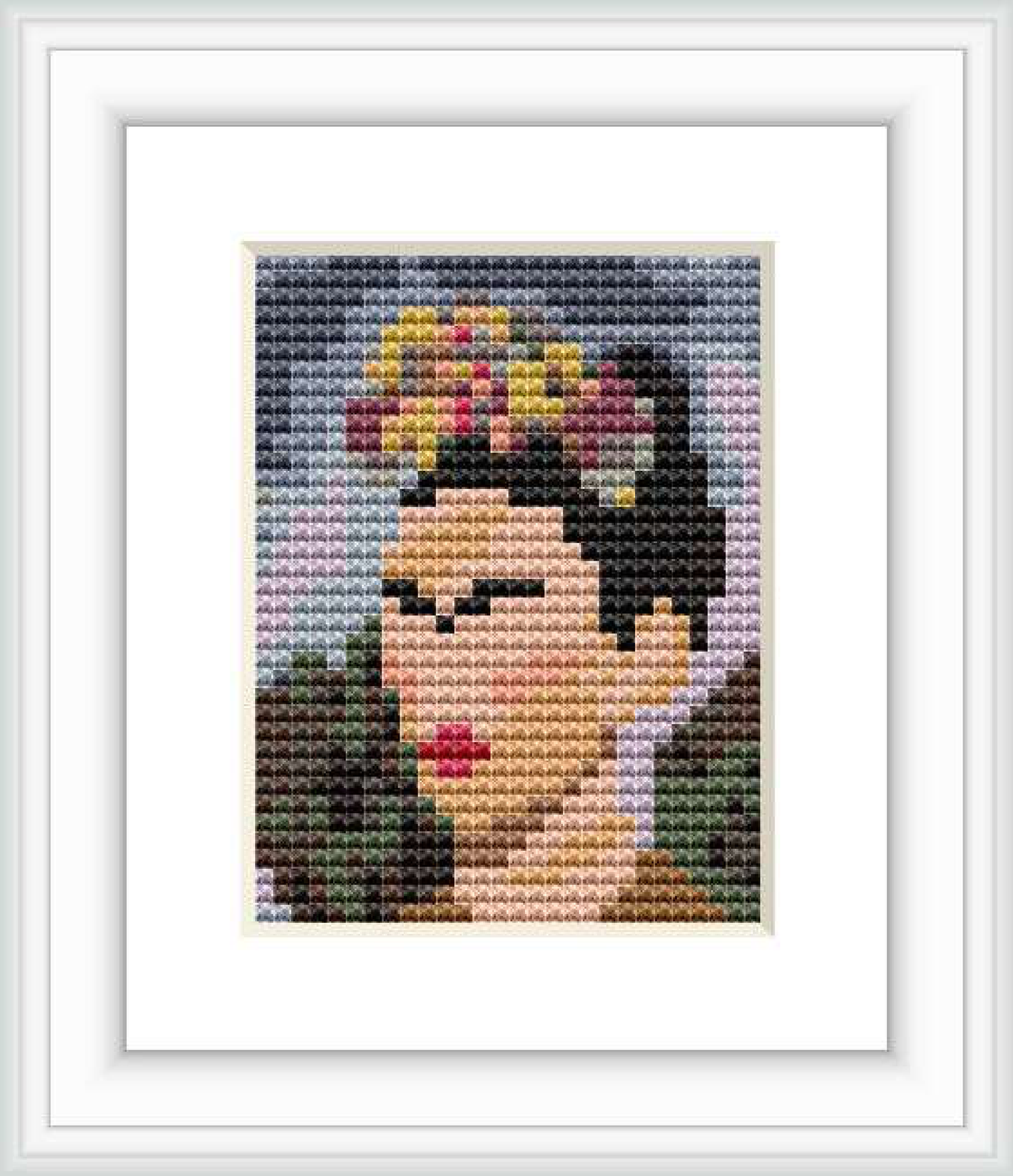 The image displays a framed cross stitch pattern depicting an abstract portrait of Frida Kahlo centered on a white background.