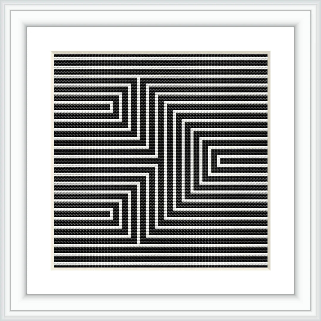 A framed cross stitch pattern with a black and white geometric arrow design creating an optical illusion, mounted on a wall or placed on a flat surface.