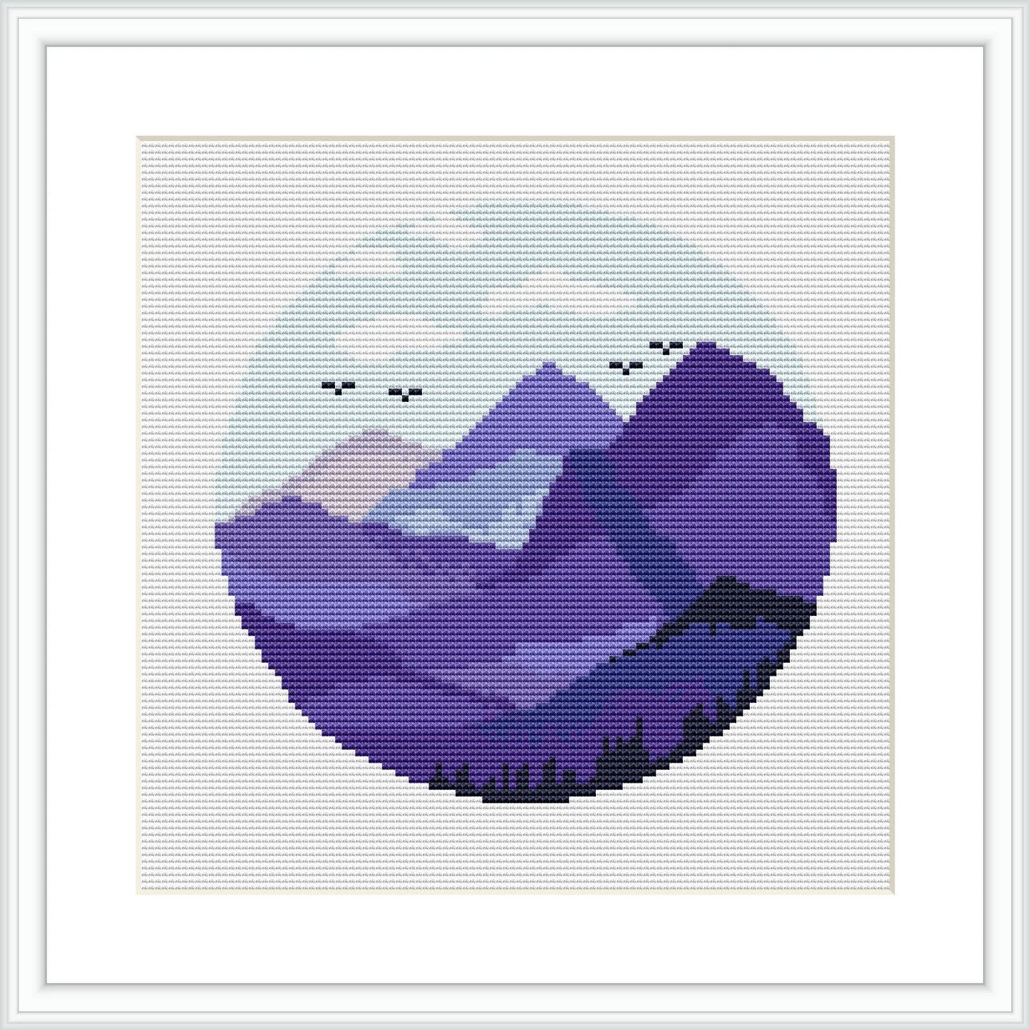 The image features a round cross-stitch pattern showing a stylized mountain landscape within a circular frame. The mountains are portrayed in various shades of purple and are complemented by a pale sky with small birds flying.