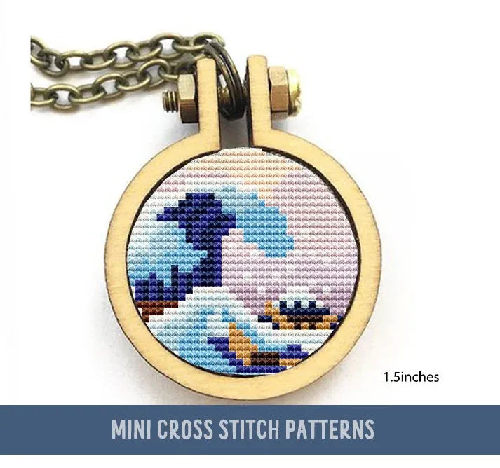 This cross stitch pattern features a stylized wave, reminiscent of Hokusai’s iconic design, set within a small circular wooden frame with a chain attached, ready for use as a pendant or keychain.