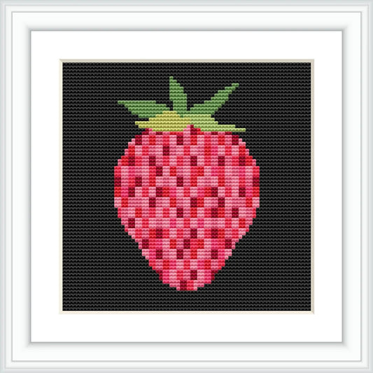 The image depicts a framed cross stitch pattern of a strawberry on black fabric. The strawberry is prominently displayed in the center, composed of various shades of pink and red squares with a crown of green stitches on top. The pattern is encased within a white square frame against a white background.