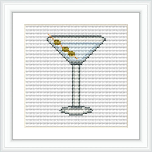 The image depicts a cross-stitch pattern of a martini glass filled with a drink and garnished with three olives on a toothpick. The glass is centrally placed within a white-background frame.