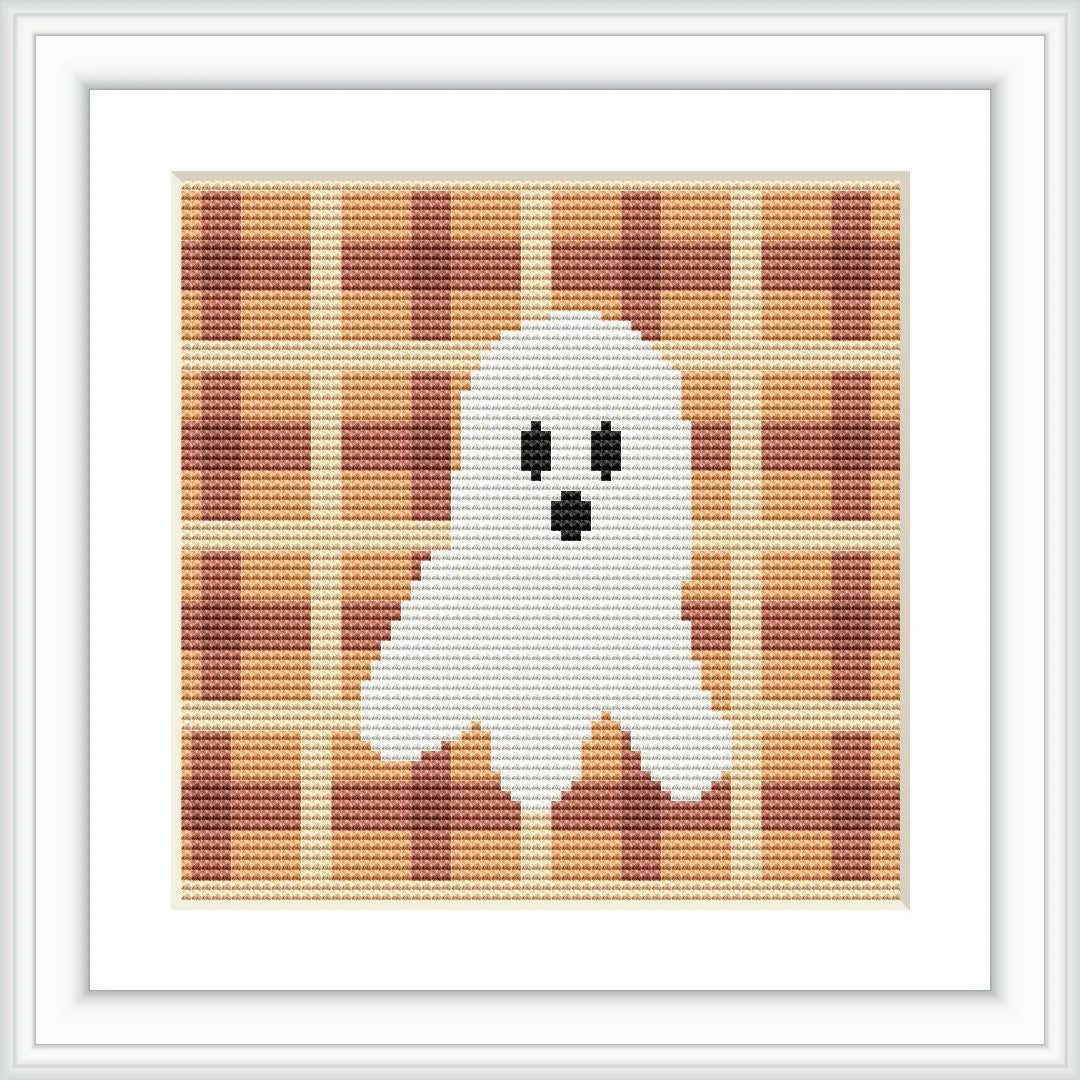 The image shows a cross stitch pattern with a white ghost with black eyes and mouth in the center, set against an orange and brown gingham checked background.