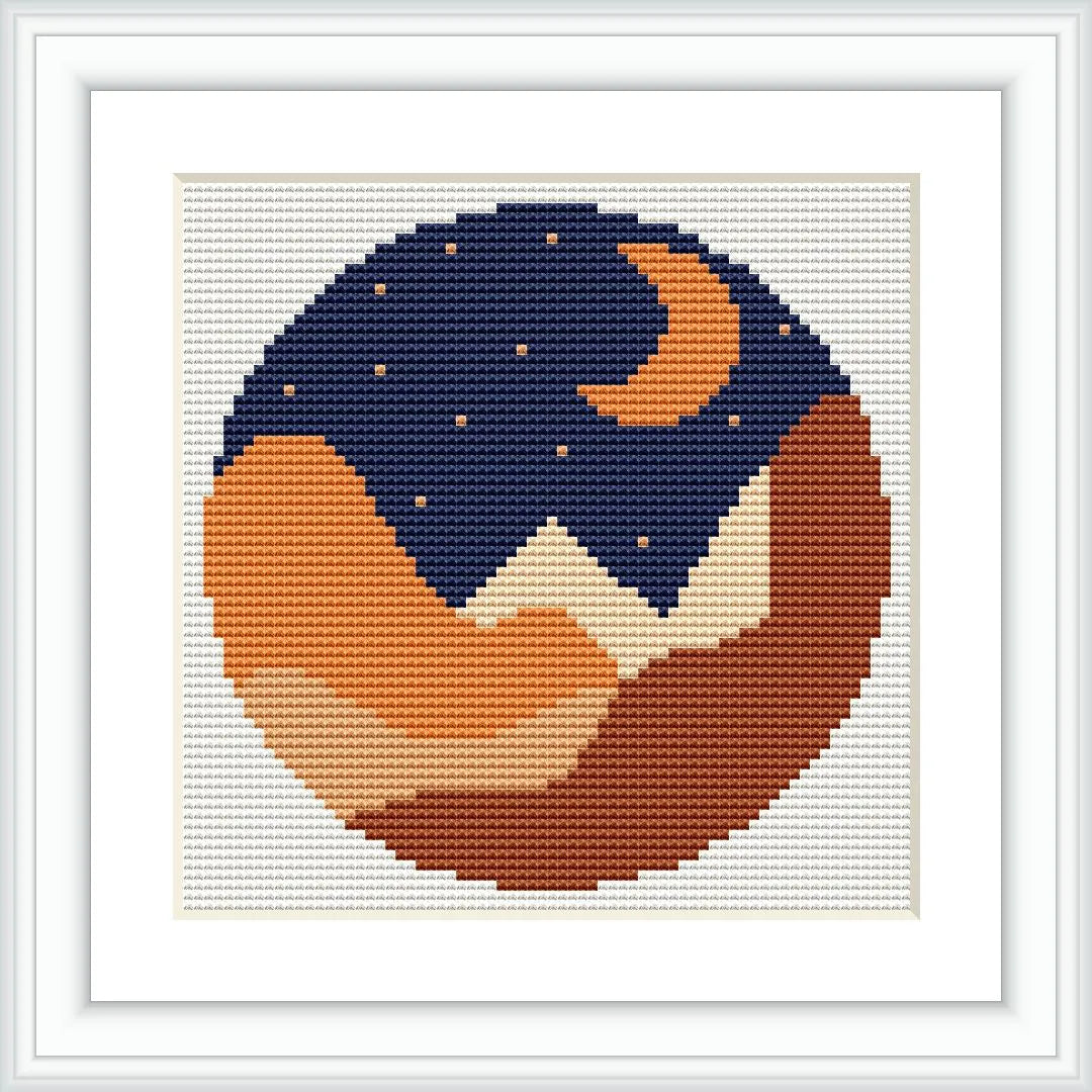 The cross stitch pattern shows a circular design of a nightscape with a crescent moon, stars, and rolling hills or mountains in shades of dark blue, orange, and brown.