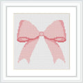 The image shows a cross-stitched pattern in the form of a pink bow. It is framed in a white, square frame, with the bow centered in the middle.