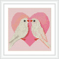 Two white birds face each other in front of a large, pink heart background. They appear to be kissing or cuddling.