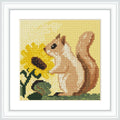 The image shows a squirrel standing on grass, facing a large sunflower. The squirrel is brown and positioned on the right, while the sunflower is yellow and on the left.