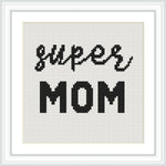 The image displays a cross stitch pattern with the words 'super mom' in black thread on a white background, framed elegantly.