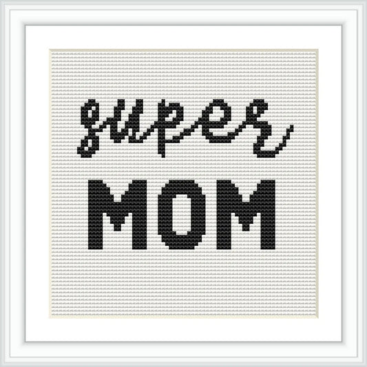 The image displays a cross stitch pattern with the words 'super mom' in black thread on a white background, framed elegantly.