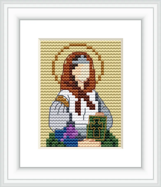 The image depicts a figure of Saint Dymphna, distinguished by a halo above her head. She is holding a book with a cross design, set against a plain background. There are flowers in front of her, adding color to the image.