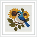 A blue bird perches on a branch surrounded by two large sunflowers and green leaves.