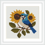 A blue bird perches on a branch surrounded by two large sunflowers and green leaves.