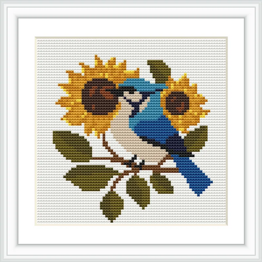 A blue bird perches on a branch surrounded by two large sunflowers and green leaves.