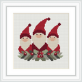 The image depicts three gnomes with red hats and white beards, adorned with holly and berries at their feet, all framed by a white border.