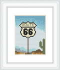The image features a Route 66 road sign set against a blue sky with a distant brown landscape and a green cactus.