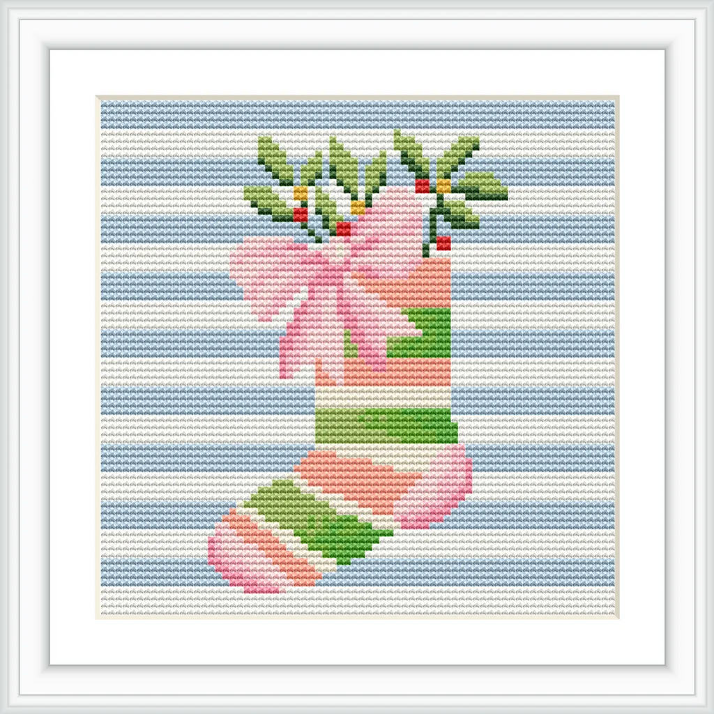 The image shows a cross stitch pattern of a Christmas stocking with green and pink stripes on a blue striped background. The stocking is adorned with a pink bow and green foliage with red berries at the top.