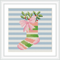 The image shows a cross stitch pattern of a Christmas stocking with green and pink stripes on a blue striped background. The stocking is adorned with a pink bow and green foliage with red berries at the top.