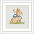 The image shows a cute brown bunny sitting on a green patch of grass. The bunny has a blue bow around its neck and is facing right.