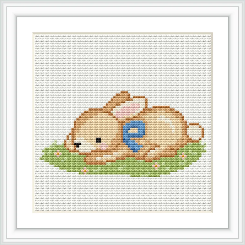 A small brown bunny with a blue patch lies peacefully on a green grassy patch with tiny flowers, framed by a white border.