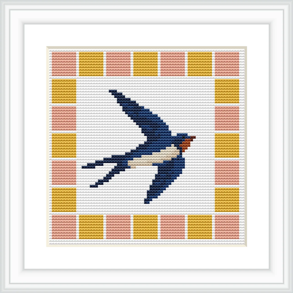 The image shows a cross stitch of a blue swallow with a white underbelly and red throat in flight, surrounded by a geometric border of squares in yellow and peach.