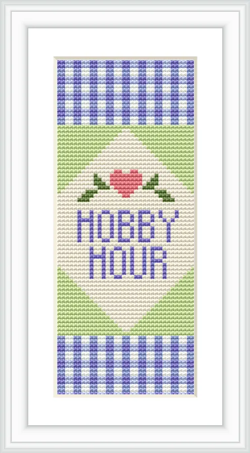 The design showcases a cross-stitched bookmark with 'Hobby Hour' text centered. Above the text is a stitched heart flanked by two leaves, framed by a blue and white checkerboard pattern on the top and bottom, with a green and white triangle motif.