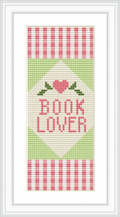 The cross-stitch pattern features the words 'BOOK LOVER' in pink text, accompanied by a heart at the top and decorative stripes in pink and green. The background is primarily white.
