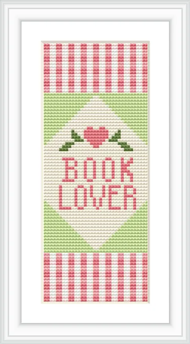 The cross-stitch pattern features the words 'BOOK LOVER' in pink text, accompanied by a heart at the top and decorative stripes in pink and green. The background is primarily white.