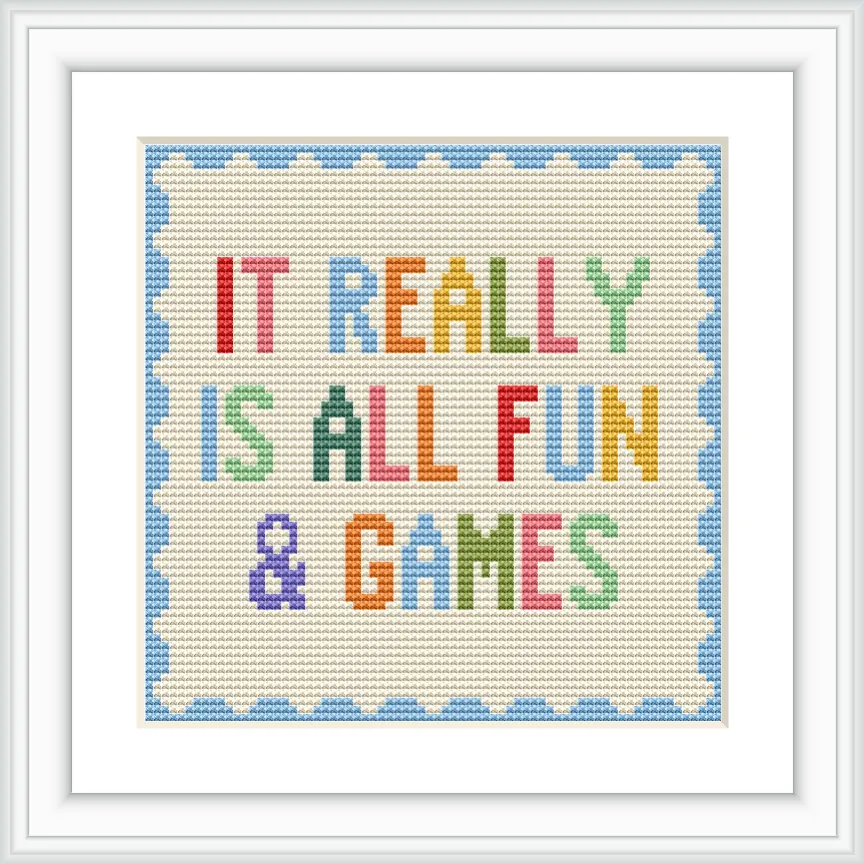 This image features a cross stitch design with the phrase 'IT REALLY IS ALL FUN & GAMES' centered. The text is multicolored with each word in a different color, surrounded by a blue scalloped border.
