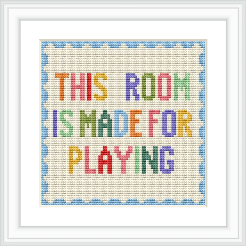 The image features a framed cross stitch with the text 'This Room is Made for Playing' in multicolored letters, bordered by a light blue scalloped edge.