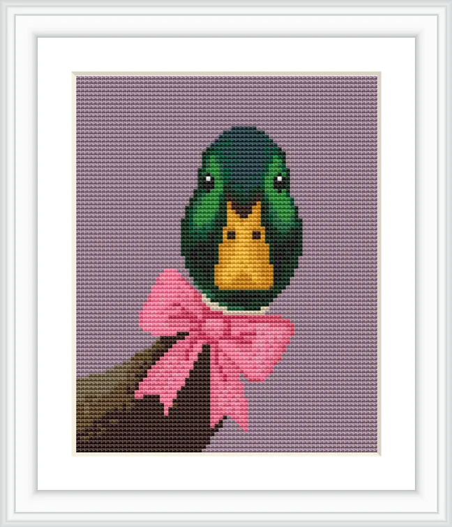 The image features a mallard head with striking green and yellow feathers, set against a soft purple background. It is adorned with a pink bow, and positioned on a branch.