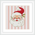 The image shows a cross-stitched Santa Claus head with a cheerful expression, wearing a red hat with a white puffball, set against a background of vertical pink and white stripes.