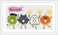 Four cartoon-style donuts, each with a different Halloween-themed character: a green Frankenstein, a black cat, a white ghost, and an orange pumpkin, each holding sparklers. The word 'Boo-nut!' is written above them in a pink speech bubble.