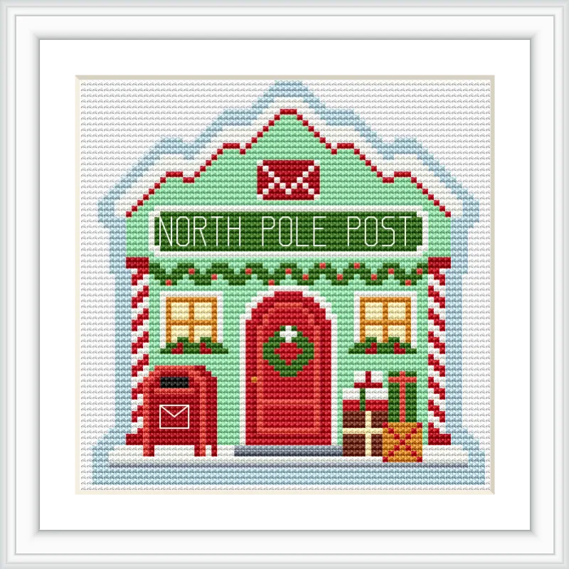 A small, festive post office building labeled 'North Pole Post' with a red door, surrounded by Christmas decorations including a mailbox, wreath, and presents.