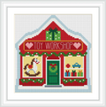 The image features a red and white toy workshop building with a snow-covered roof. The front displays Christmas decorations, toys, and gift boxes.