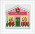 The image depicts a quaint, pink-colored Christmas flower shop with 'Christmas Flowers' written on the facade. It features decorative wreaths, potted poinsettias, and a green door presumably set for the holiday season.