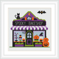 The image depicts a colorful bakeshop with a purple and black awning, adorned with a crescent moon and stars. Two pumpkins with carved faces sit outside the shop, while a black cat and a bat add to the Halloween theme.