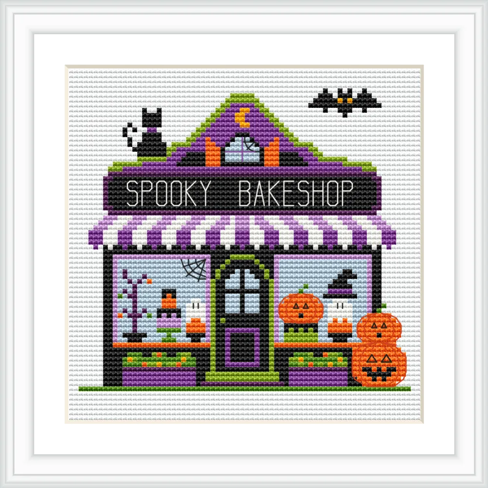The image depicts a colorful bakeshop with a purple and black awning, adorned with a crescent moon and stars. Two pumpkins with carved faces sit outside the shop, while a black cat and a bat add to the Halloween theme.