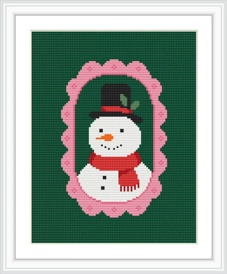The image shows a snowman with a black top hat, red scarf, and buttons, centered inside a pink scalloped oval frame, all set against a green background.