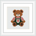 The image shows a cute brown bear wearing green overalls and a red and white striped shirt, centered on a white background. The overalls have an 'A' monogram on the chest.