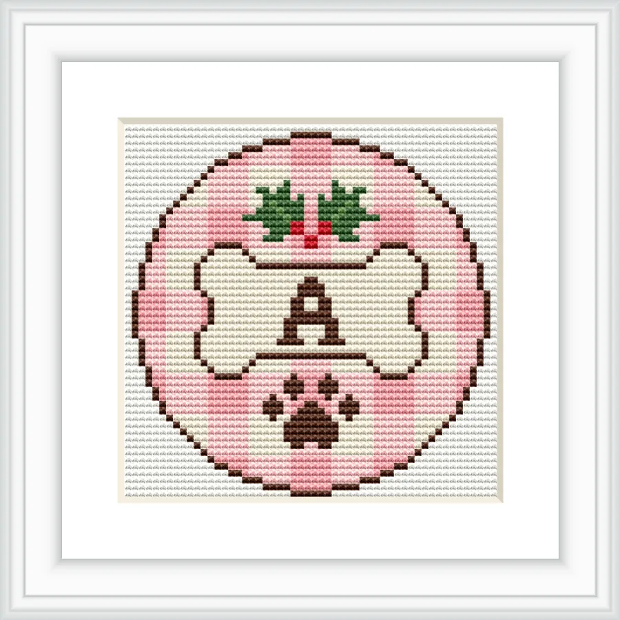 Cross stitch pattern features a circular design with a bone in the center, bordered by a pink checkered pattern. Above the bone is a floral decoration, and below is a paw print. The letter 'A' is prominently displayed on the bone.