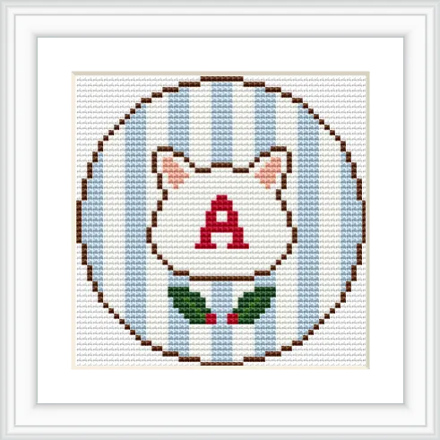 The image features a cross stitch pattern of a cat's head with pointed ears and the letter 'A' in red on the face. The background is composed of vertical blue and white stripes, and there is a small green wreath at the bottom.