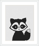 The cross stitch pattern features a stylized raccoon with large expressive eyes and alternating black and white patterns, resembling pixel art. This is framed on a white canvas, ready for embroidery.