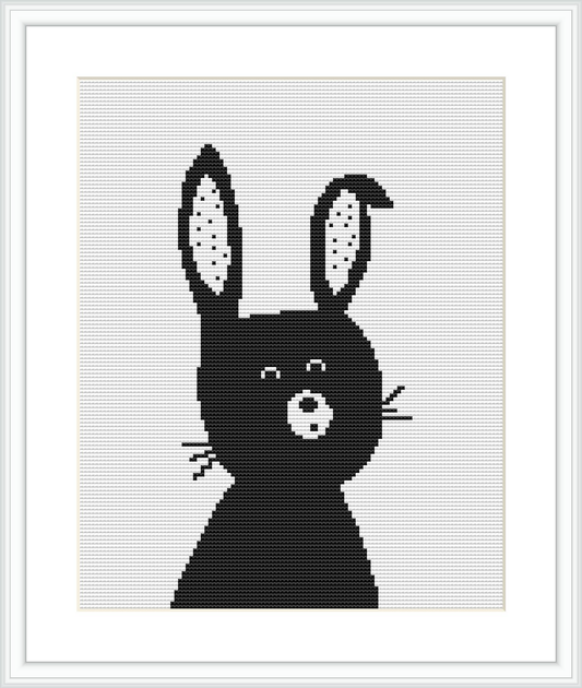 The image displays a cross stitch pattern of a stylized black bunny silhouette centered on a white fabric background, framed in a simple square frame.