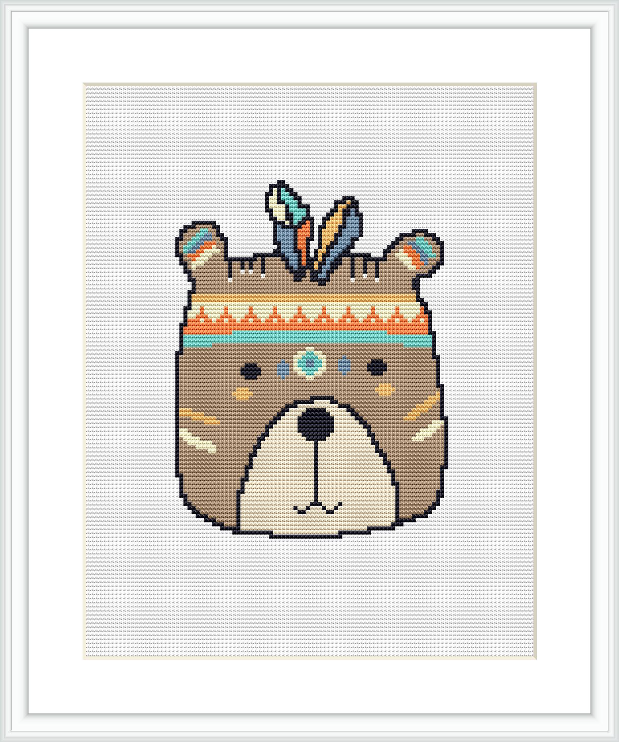 A cross stitch pattern featuring a stylized bear face with tribal-inspired decorative elements, framed and displayed against a white background.