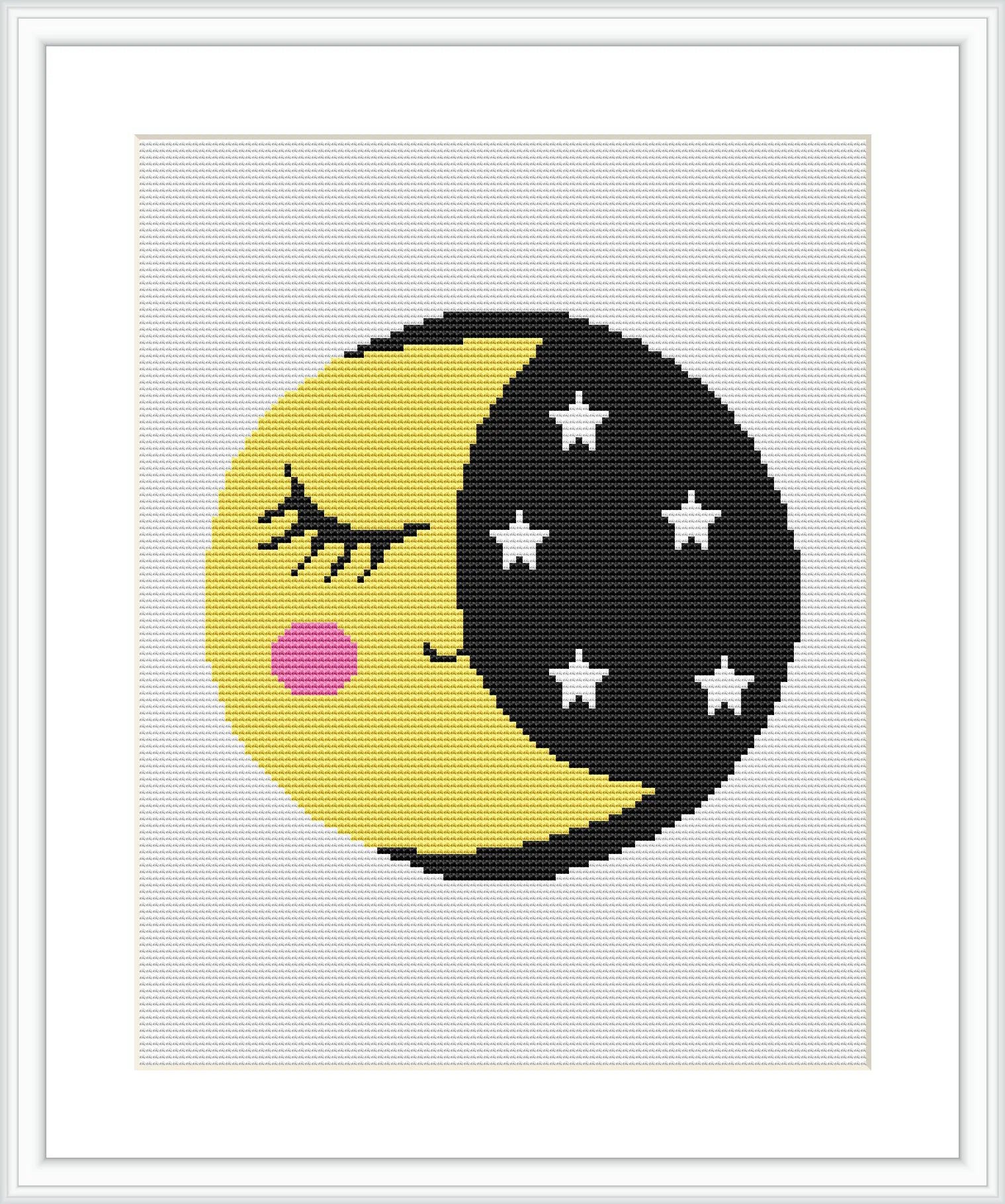 The image showcases a framed cross stitch pattern featuring a stylized half-black, half-yellow moon with a sleeping face on the yellow side and stars on the black side.