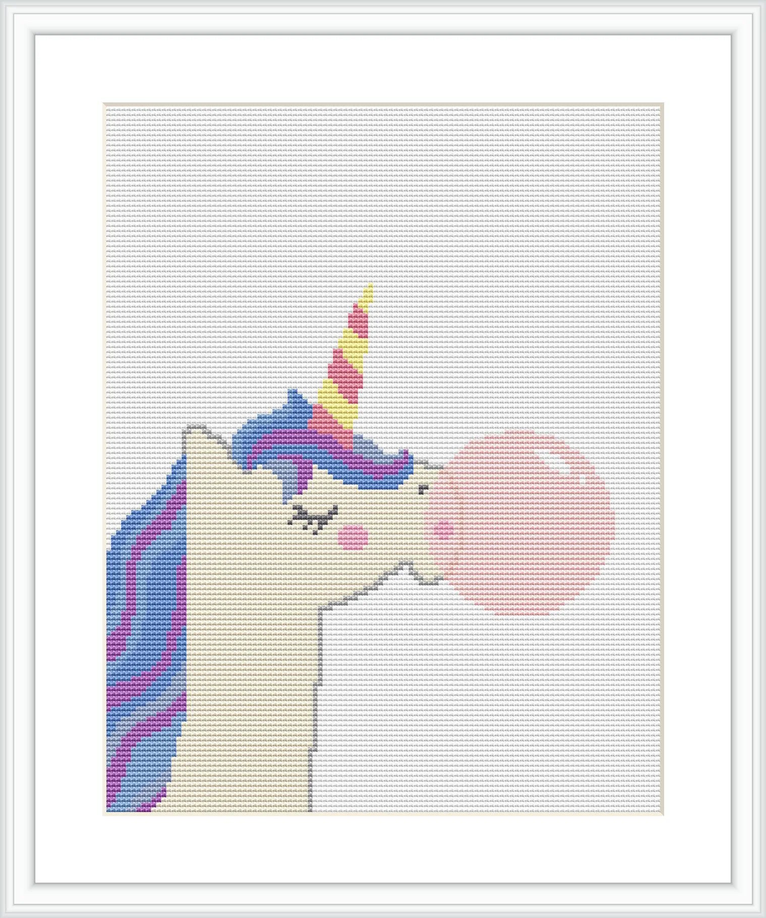 The image depicts a cross stitch pattern framed within a square frame. The design shows an upright unicorn profile with closed eyes and lashes, blowing a large pink bubblegum bubble from its mouth. The unicorn's mane and horn feature a gradient of yellow, blue, and purple. The background is plain, letting the unicorn stand out.