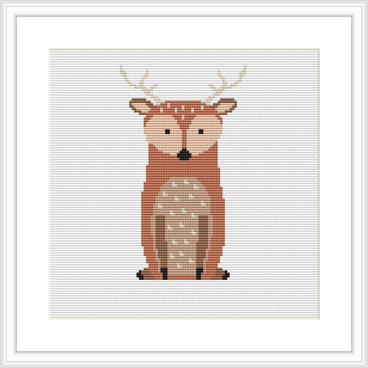 The image shows a cross stitch pattern of a stylized deer centrally placed on a white canvas within a square grid. The deer is depicted with a warm brown and beige color palette and features distinct white spots and black details for the eyes and hooves. The pattern is framed by a simple white border.