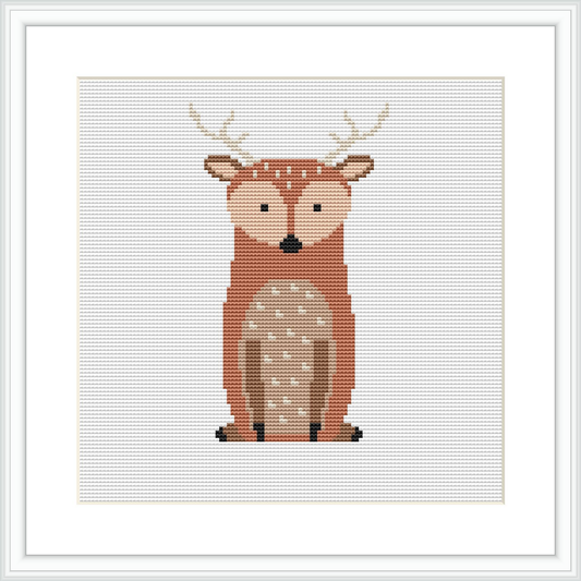 The image shows a cross stitch pattern of a stylized deer centrally placed on a white canvas within a square grid. The deer is depicted with a warm brown and beige color palette and features distinct white spots and black details for the eyes and hooves. The pattern is framed by a simple white border.