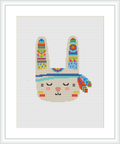 The image displays a framed cross stitch pattern of a stylized rabbit head with tribal decorations against a white background.