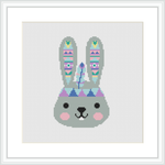 The image displays a framed cross stitch pattern of a stylized bunny with tribal patterns on its ears, and pastel-colored geometric shapes adorning its face, against a white background.